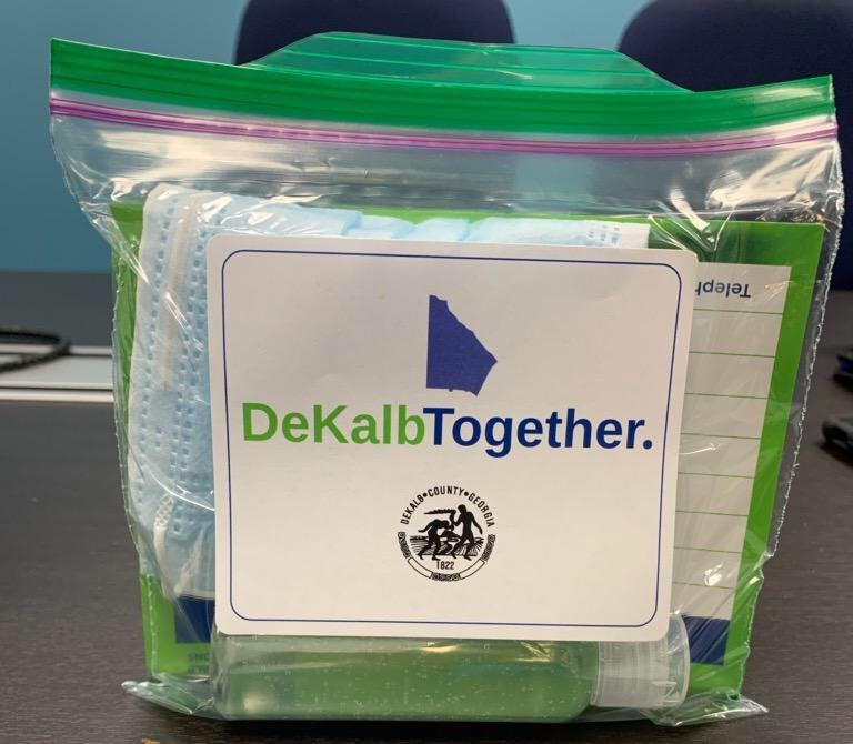 A bag containing a face mask and hand sanitizer with the DeKalb County seal and logo that says DeKalb Together.