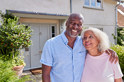 Smiling senior couple outside their home