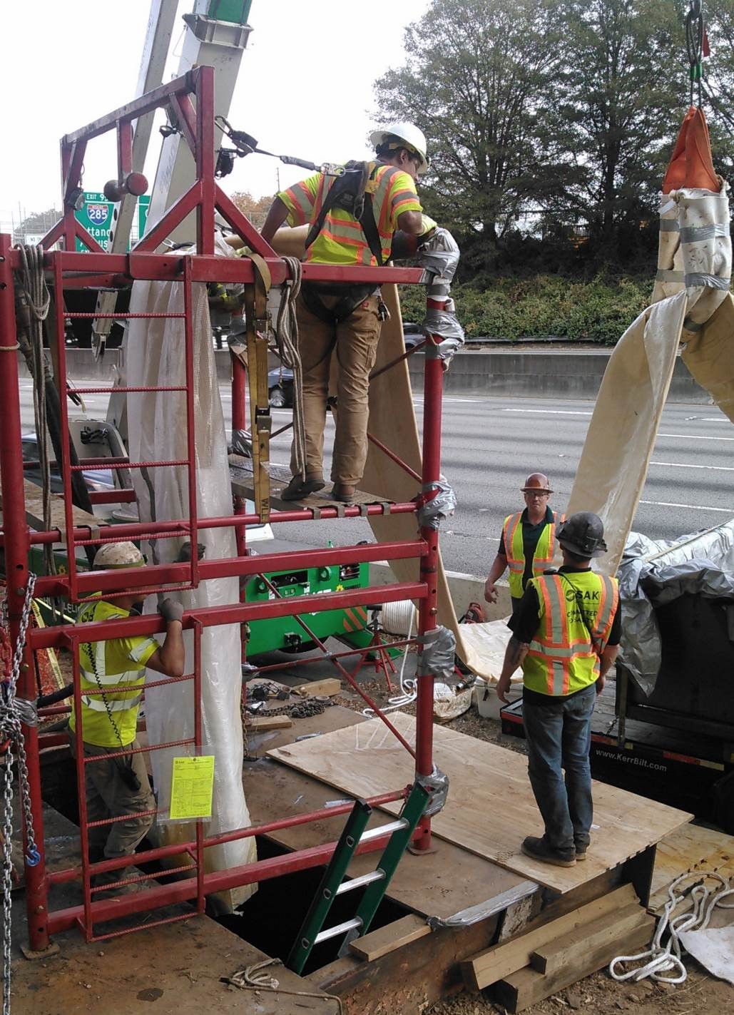 Crews lower pipe liner into trench near I-85